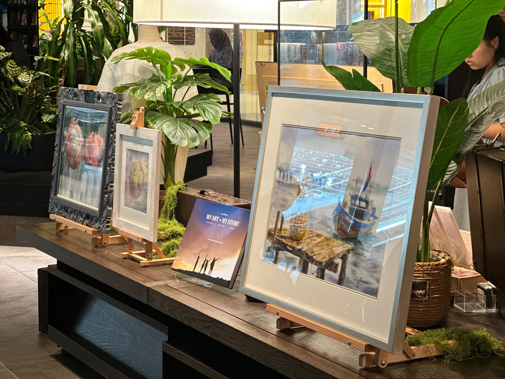 Artworks on easels beside the MY ART, MY STORY book
