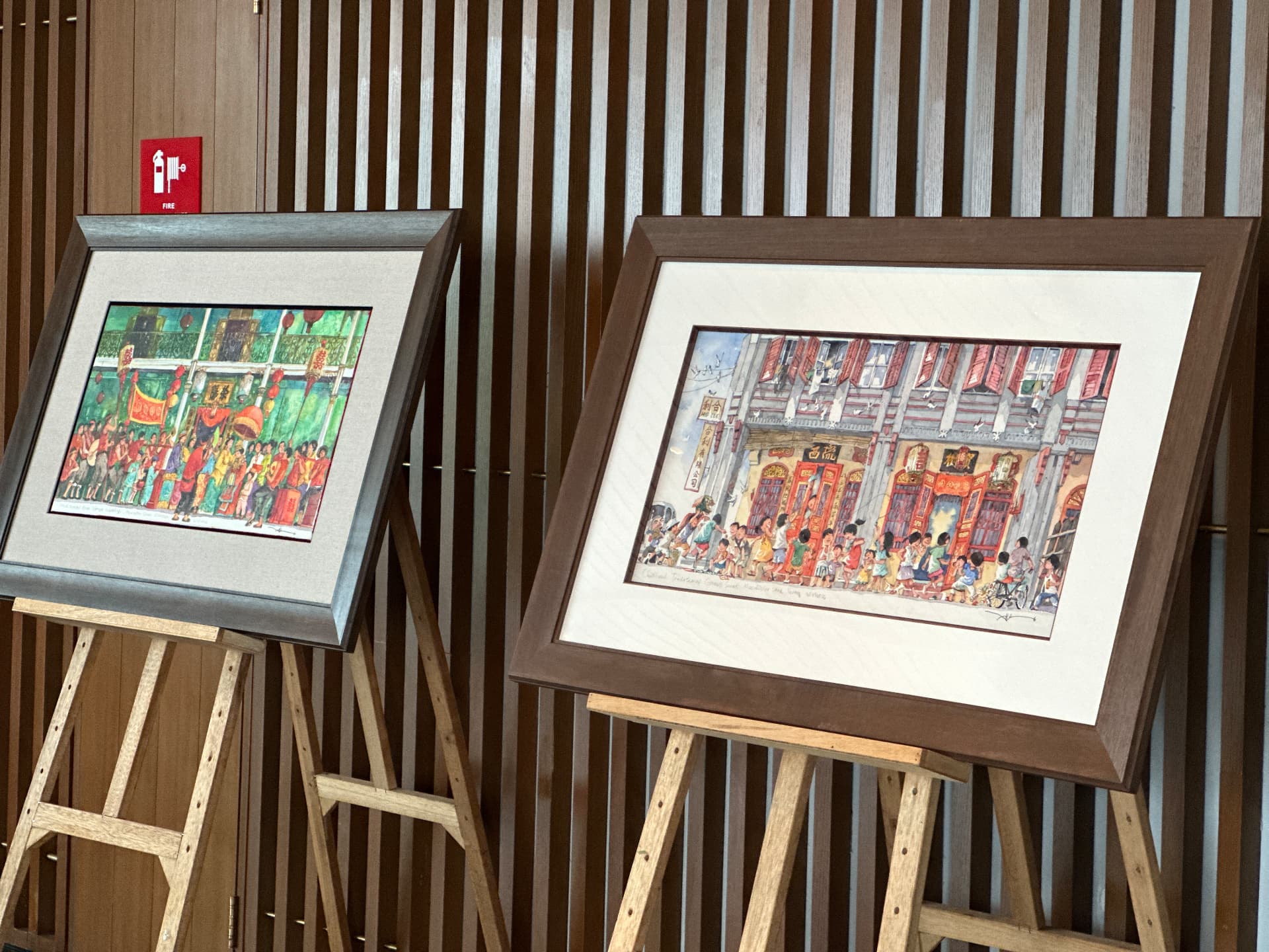 Two framed watercolours depicting lively Malaysian heritage scenes