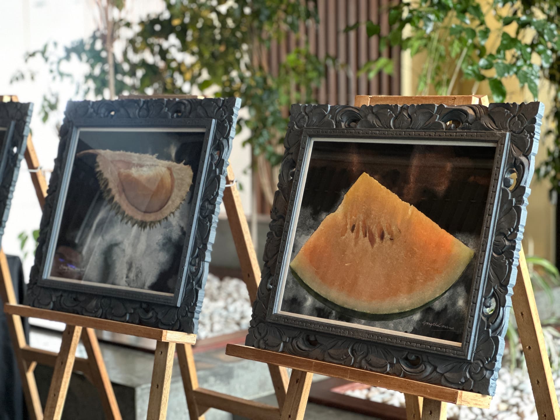 Framed durian and watermelon paintings displayed together on easels